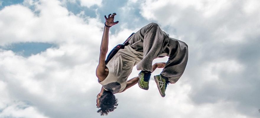 Male performing a back flip with clouds in the background