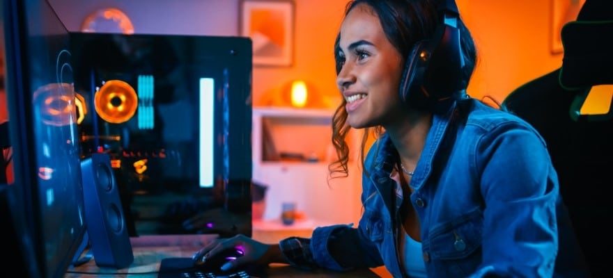 Gamer girl behind PC with headphones on and smiling